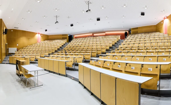 Eine Wissenschaftlerin und ein Wissenschaftler arbeiten hinter einer Glasfassade und mischen Chemikalien mit Großgeräten.
