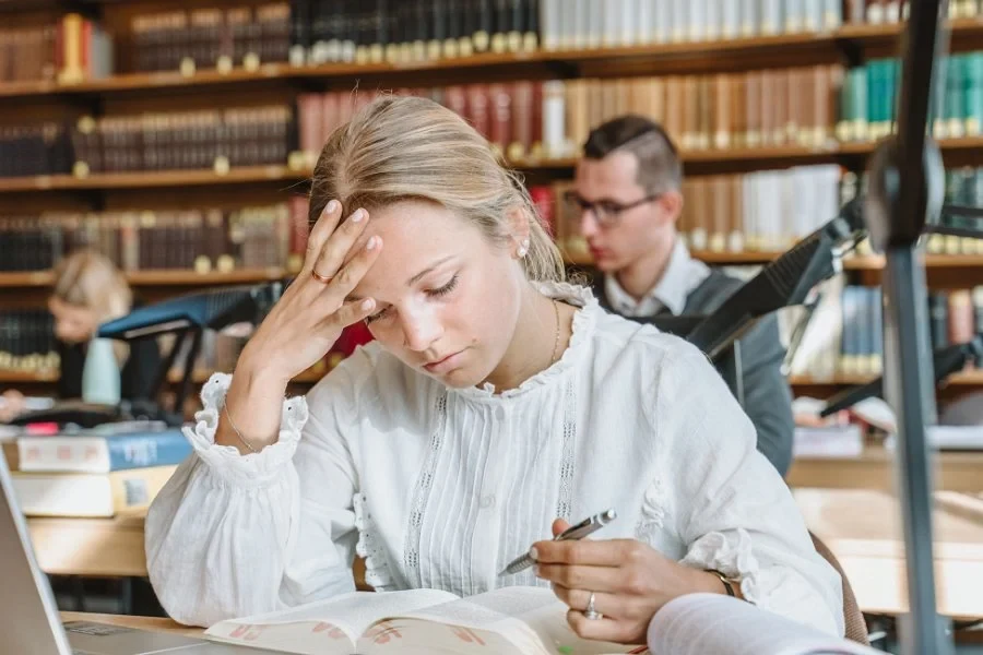 Eine Wissenschaftlerin und ein Wissenschaftler arbeiten hinter einer Glasfassade und mischen Chemikalien mit Großgeräten.